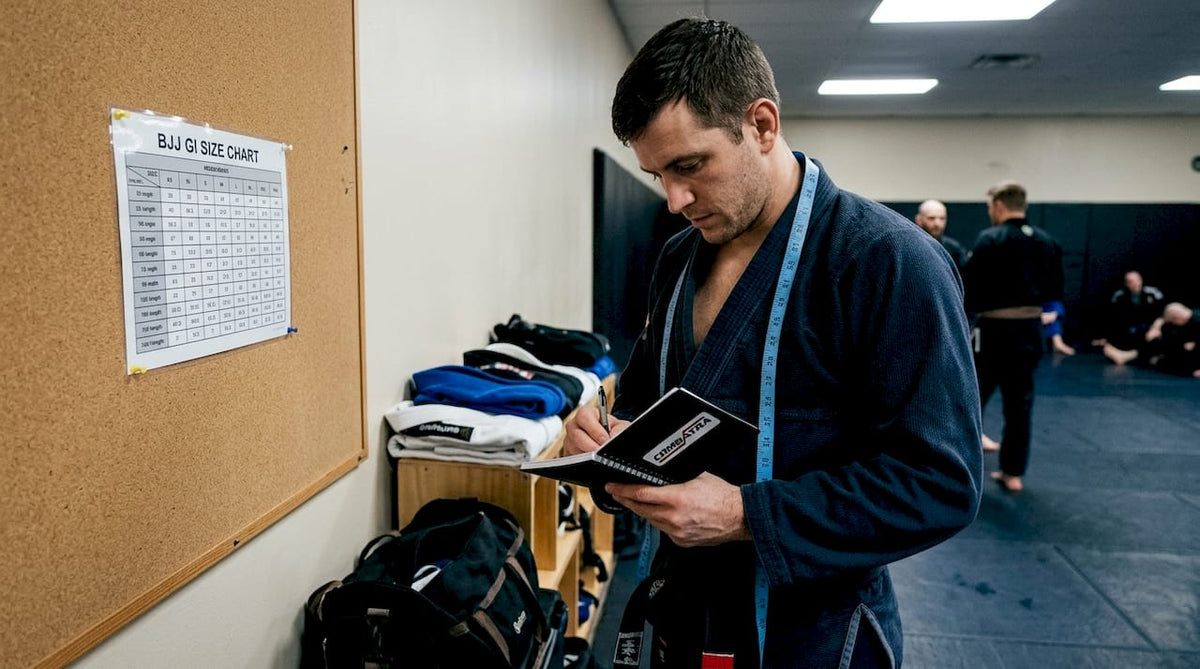 Person referencing BJJ gi size chart at gym