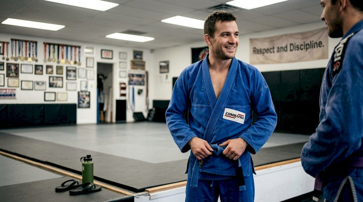 BJJ student tying belt in lively gym